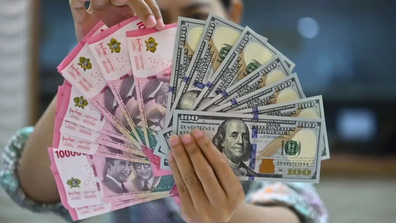 ILUSTRASI. Petugas menjunjukkan uang pecahan dolar AS dan rupiah di gerai penukaran mata uang asing di Jakarta