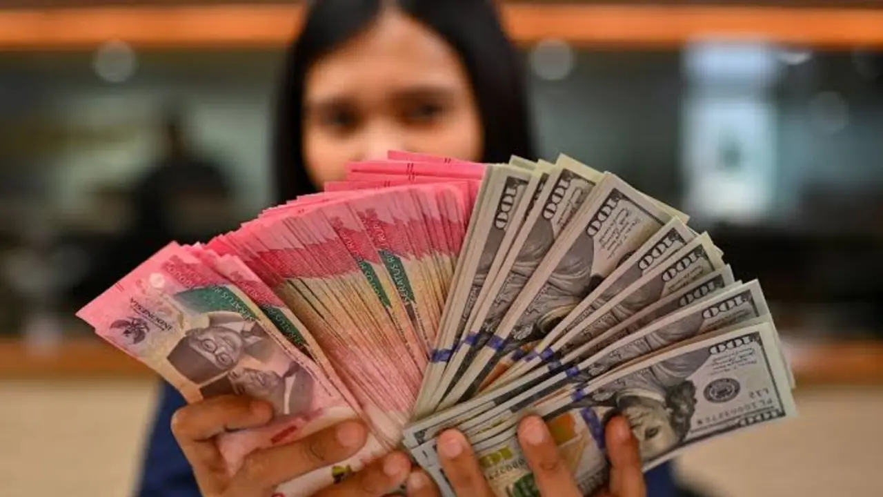Seorang karyawan bank sedang memperlihatkan uang rupiah dan dolar as